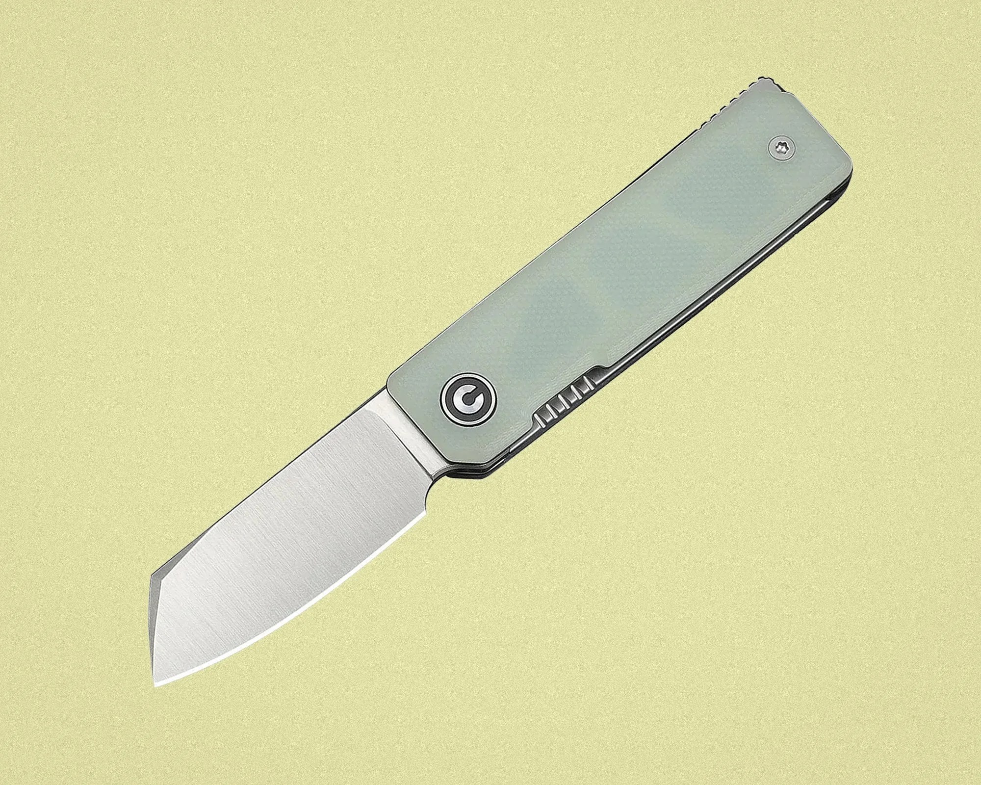 Folding knife with a brushed steel blade and light green textured handle on a pale yellow background.