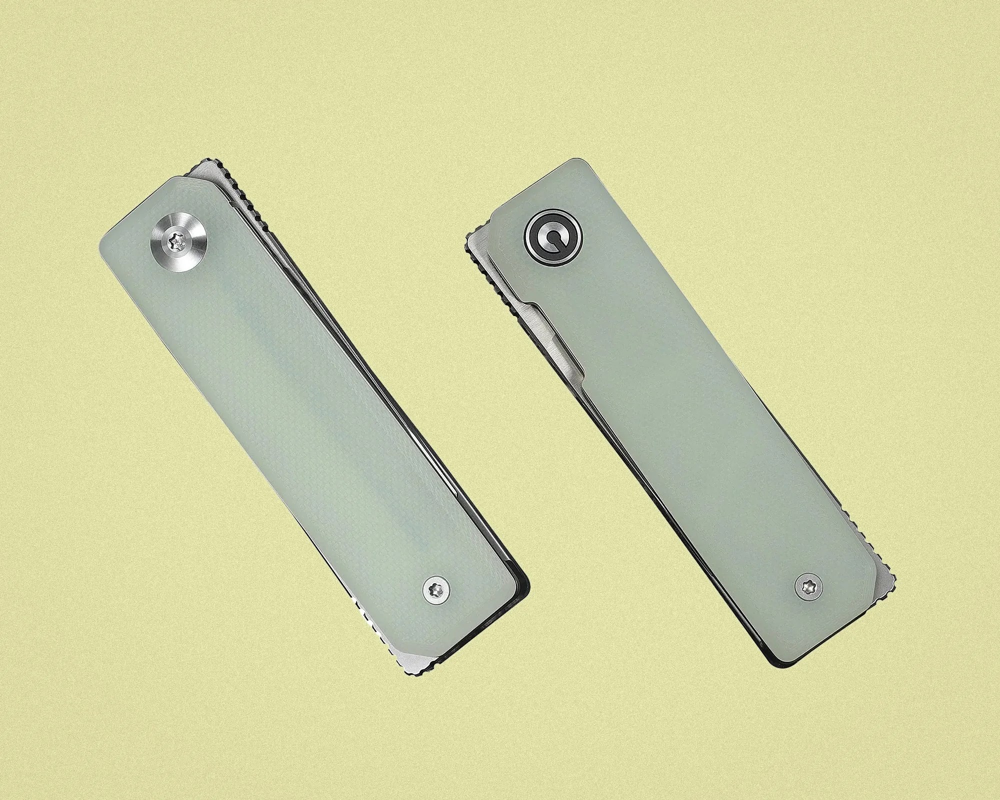 Two closed folding knives with light gray handles and visible screws on a pale yellow background.