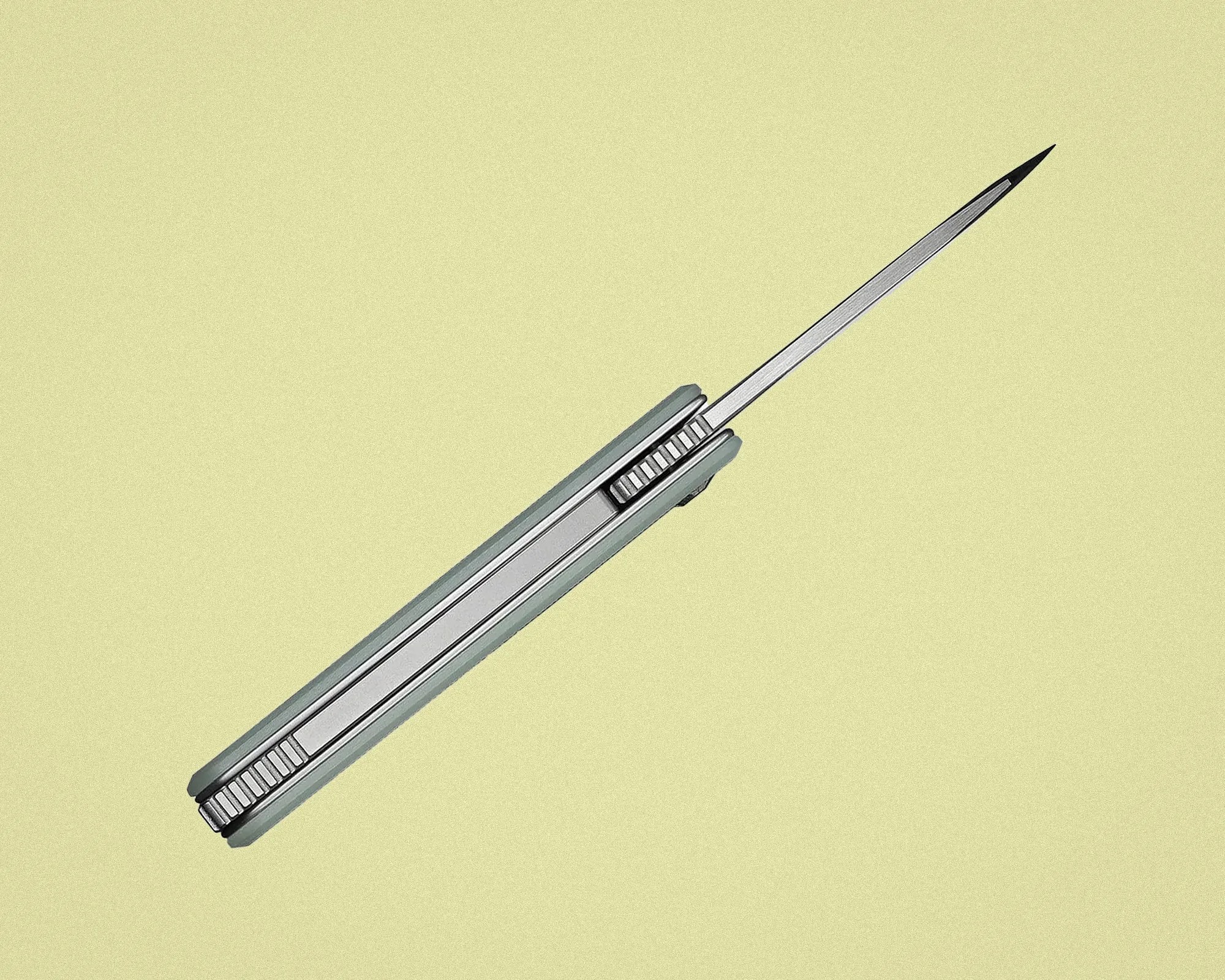 Slim silver folding knife with a pointed blade extended against a light yellow background.