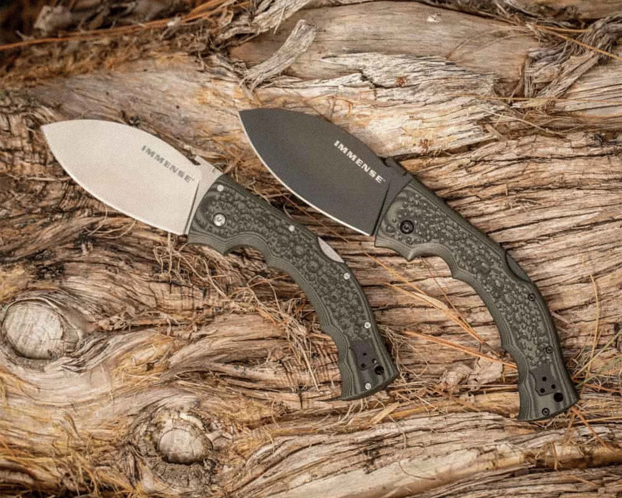 Two folding knives with textured green handles and blades labeled "IMMENSE" on a wooden surface.