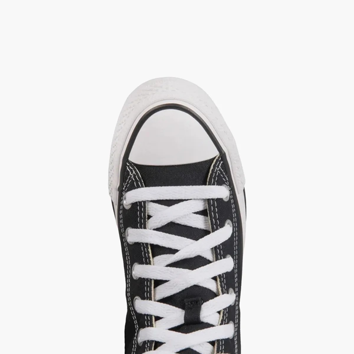 Black canvas sneaker with white rubber toe cap and white laces viewed from above.