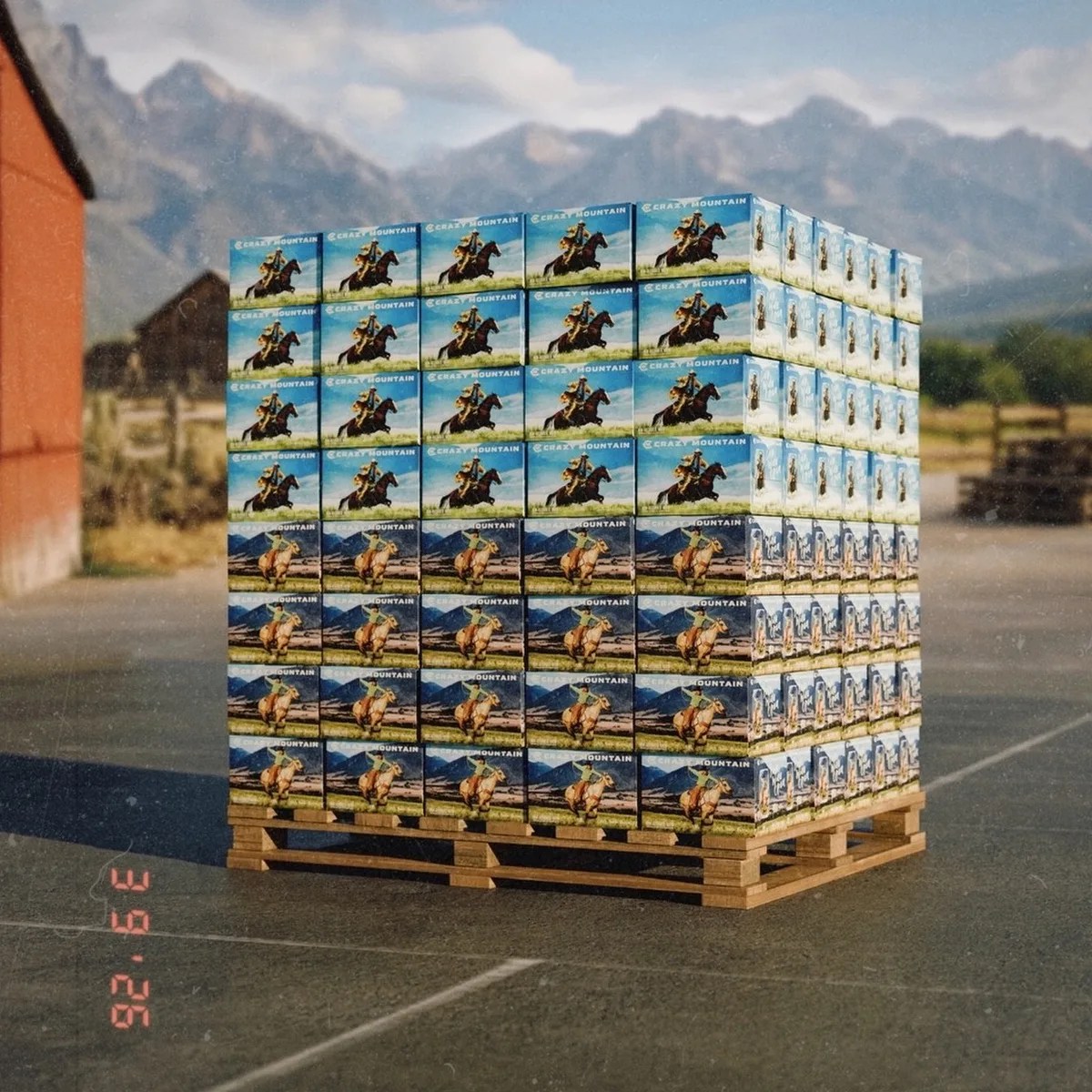 Stack of "Crazy Mountain" branded boxes with horse rider images on a wooden pallet outdoors with mountains in the background.