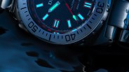 Close-up of a stainless steel dive watch with luminous blue markers and a rotating bezel showing 30 and 40.