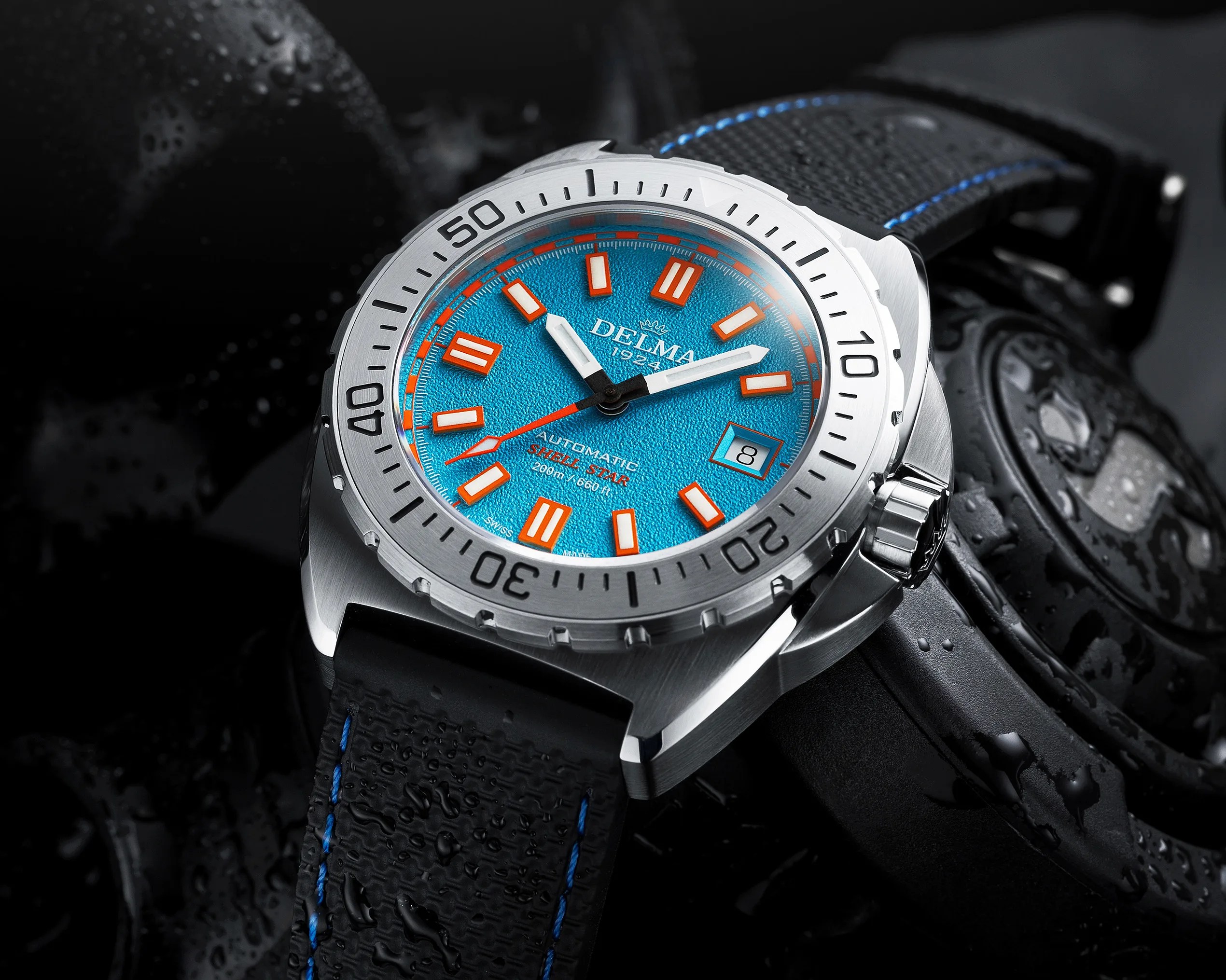Silver dive watch with bright blue textured dial, orange markers, and black strap with blue stitching.