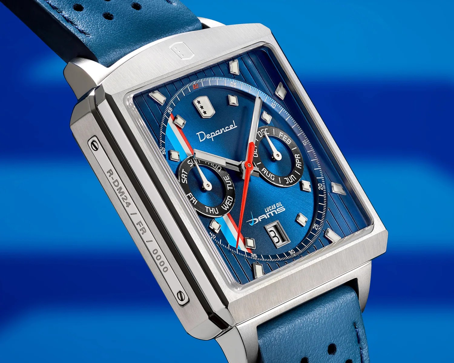 Square silver watch with blue dial, red and white hands, two subdials, and blue leather strap.