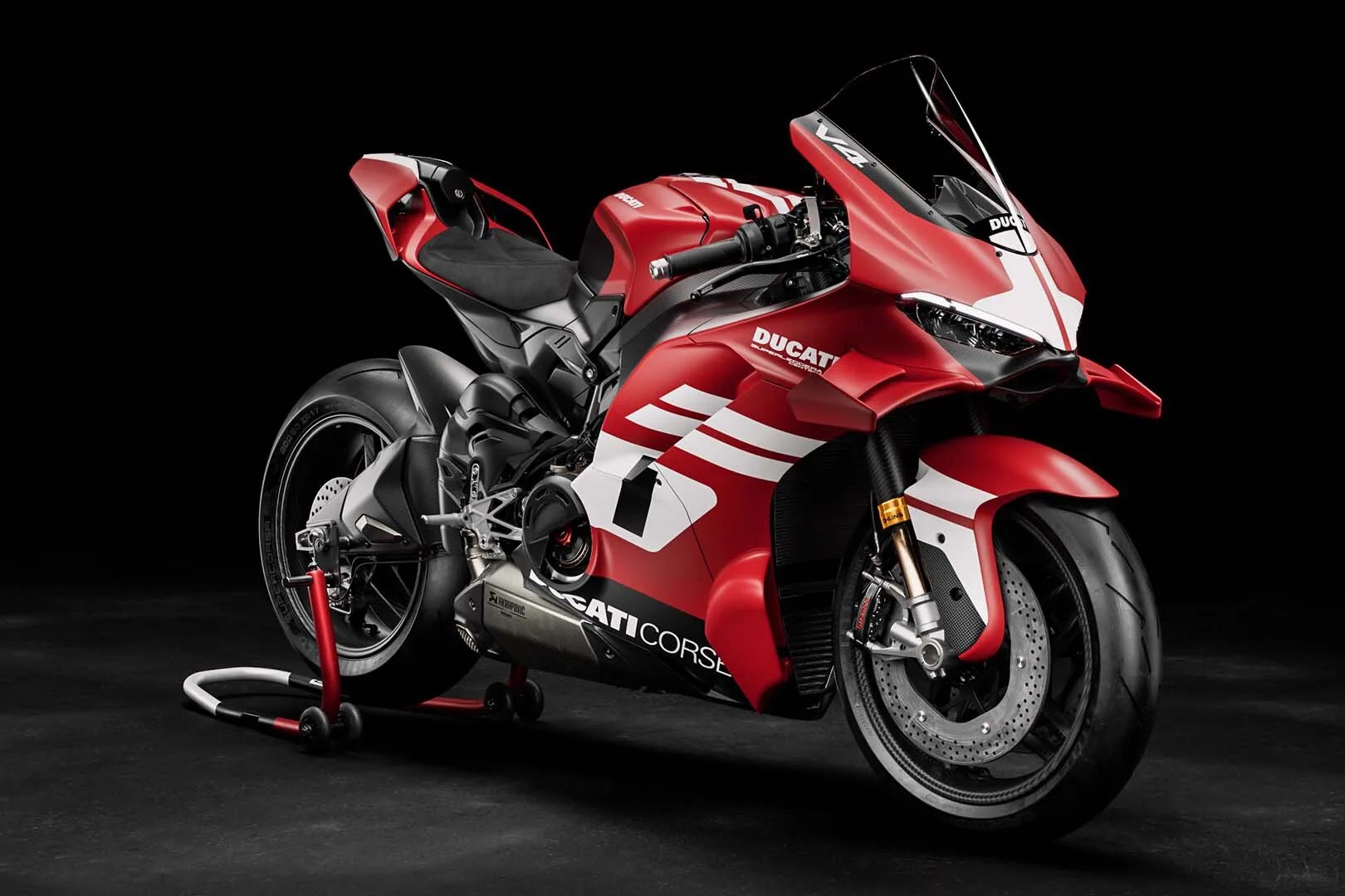 Red Ducati Corse sport motorcycle with white racing stripes on a black background.