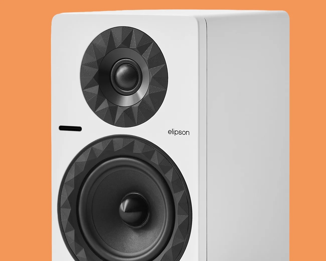 White Elipson speaker with black textured circular drivers on an orange background.
