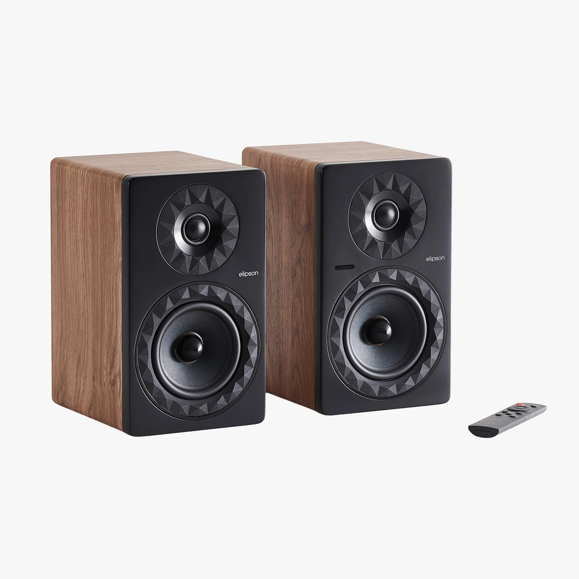 Pair of Elipson bookshelf speakers with wood finish and black front panels, shown with a small remote control.
