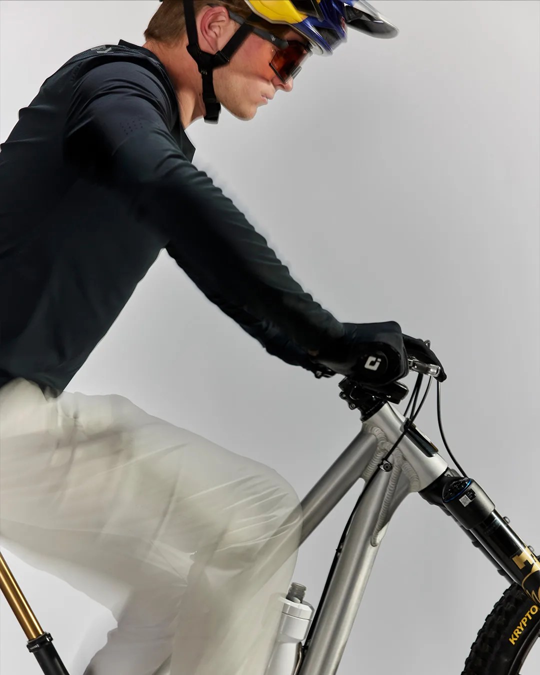 Person wearing a black long-sleeve shirt, gloves, and helmet riding a silver mountain bike with a water bottle.