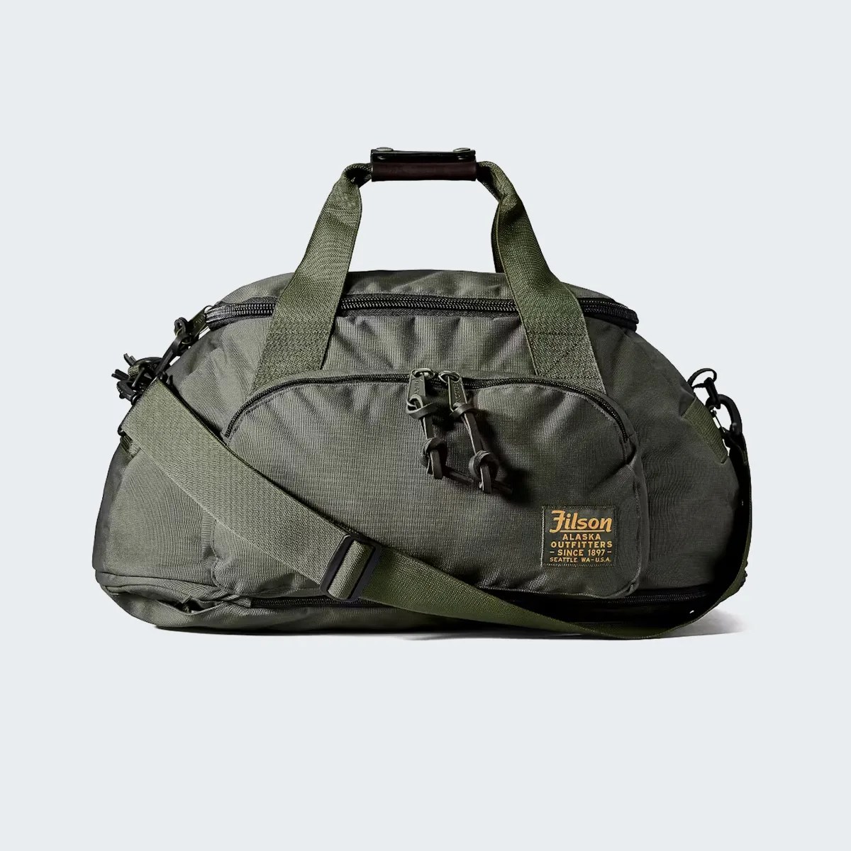 Olive green Filson duffel bag with front zip pocket and adjustable shoulder strap on a white background.