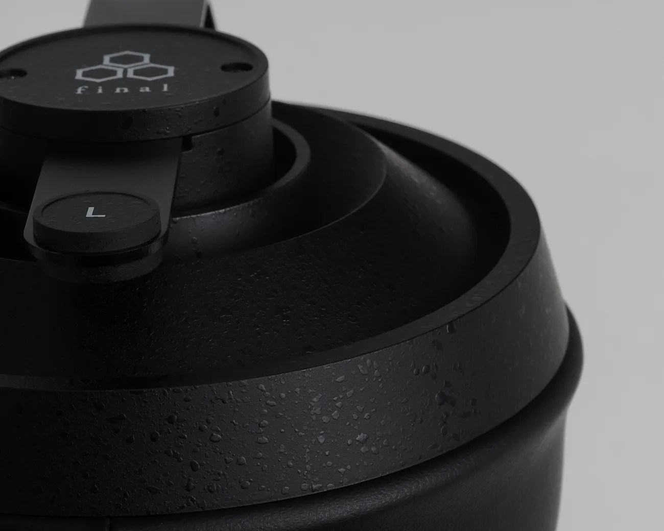 Close-up of a black textured headphone ear cup with a visible "L" left side marker and "final" logo on the hinge.