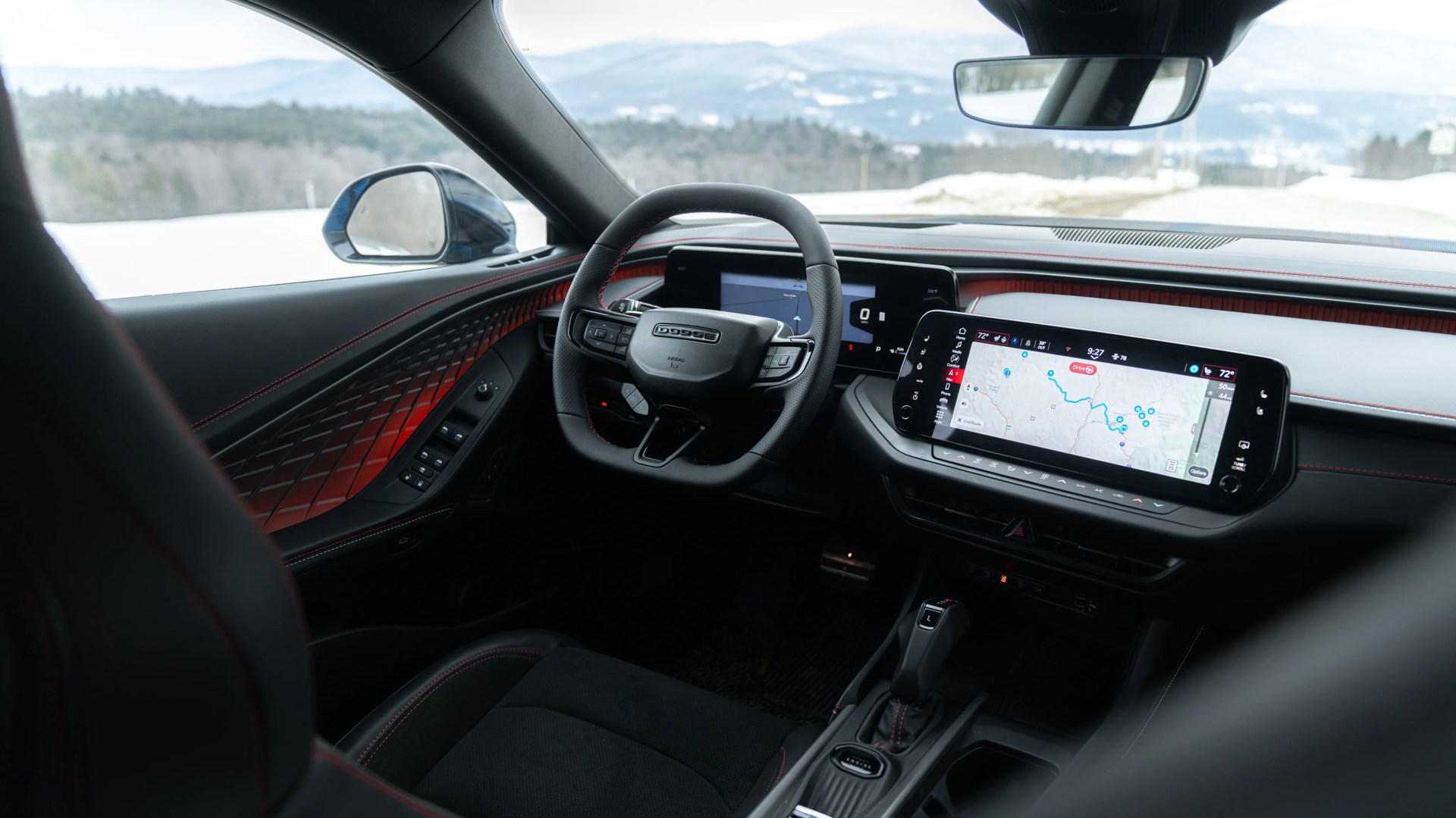 Interior of a Dodge vehicle showing a black steering wheel with Dodge logo, digital dashboard, and touchscreen navigation display.