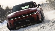 Red electric SUV driving through snow with water splashing around the tires.