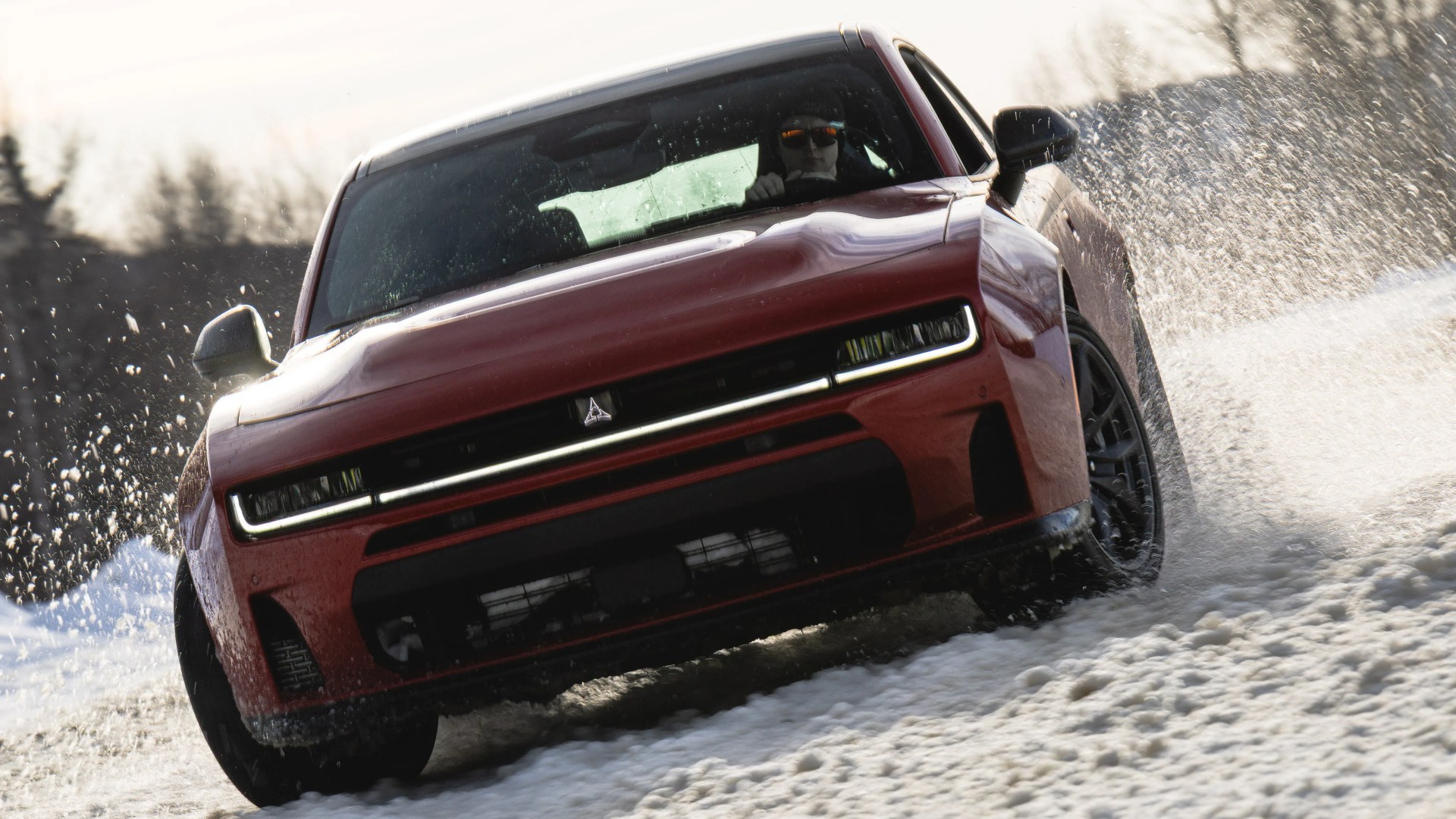 Red electric SUV driving through snow with water splashing around the tires.