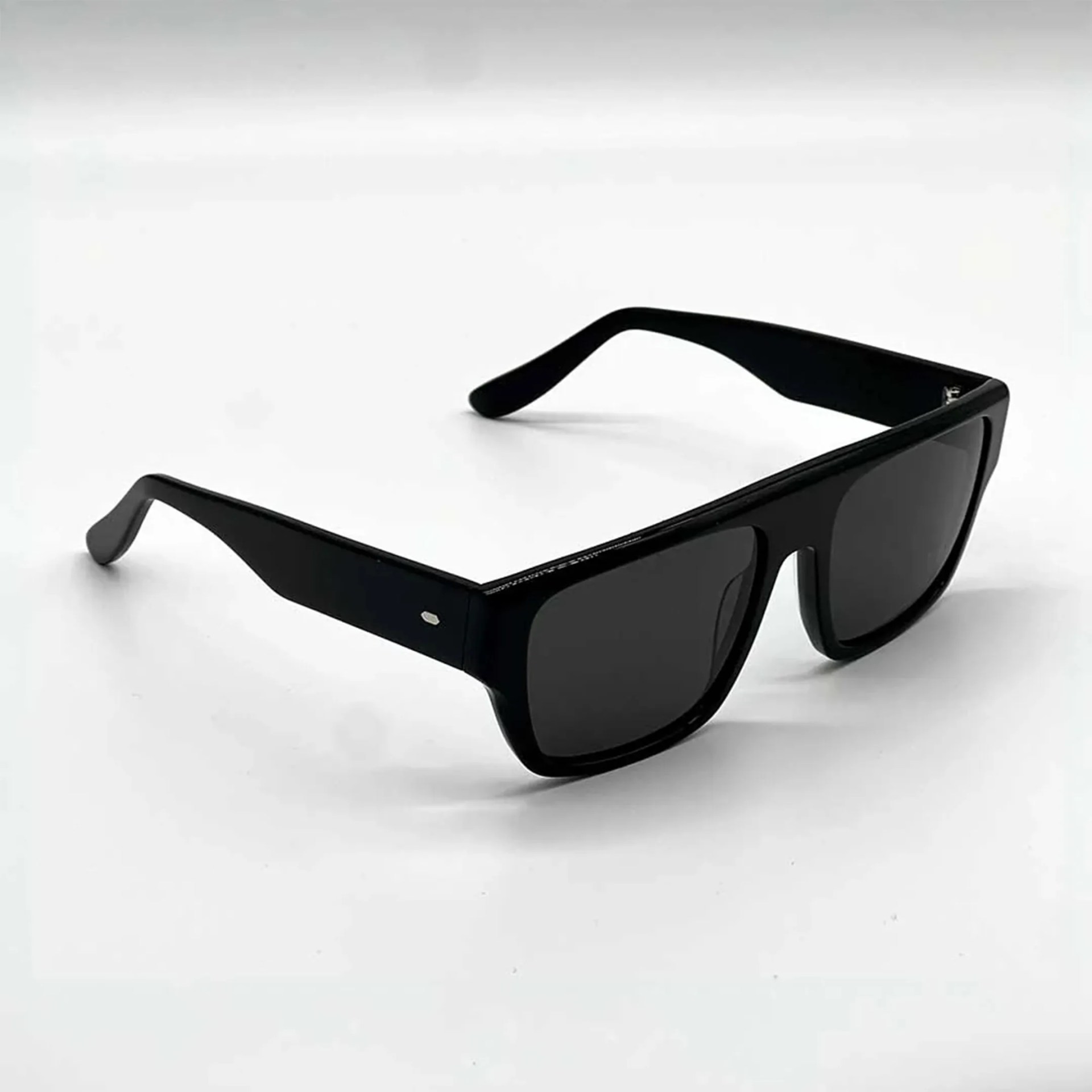 Black rectangular sunglasses with thick frames and dark lenses on a white surface.