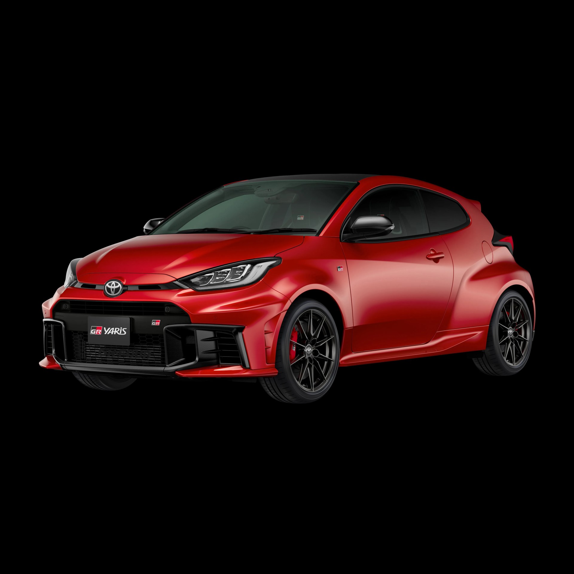 Red Toyota GR Yaris hatchback with black roof and sporty black alloy wheels on a black background.