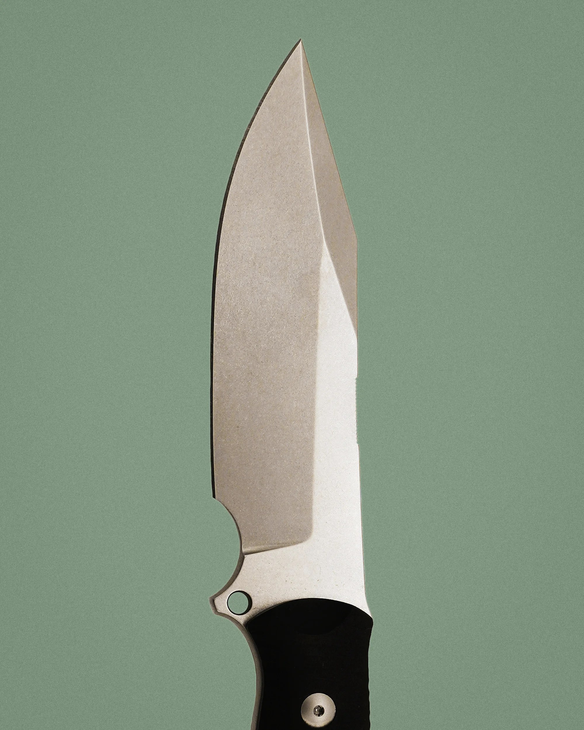 Knife blade with a stonewashed finish and a black handle against a green background.
