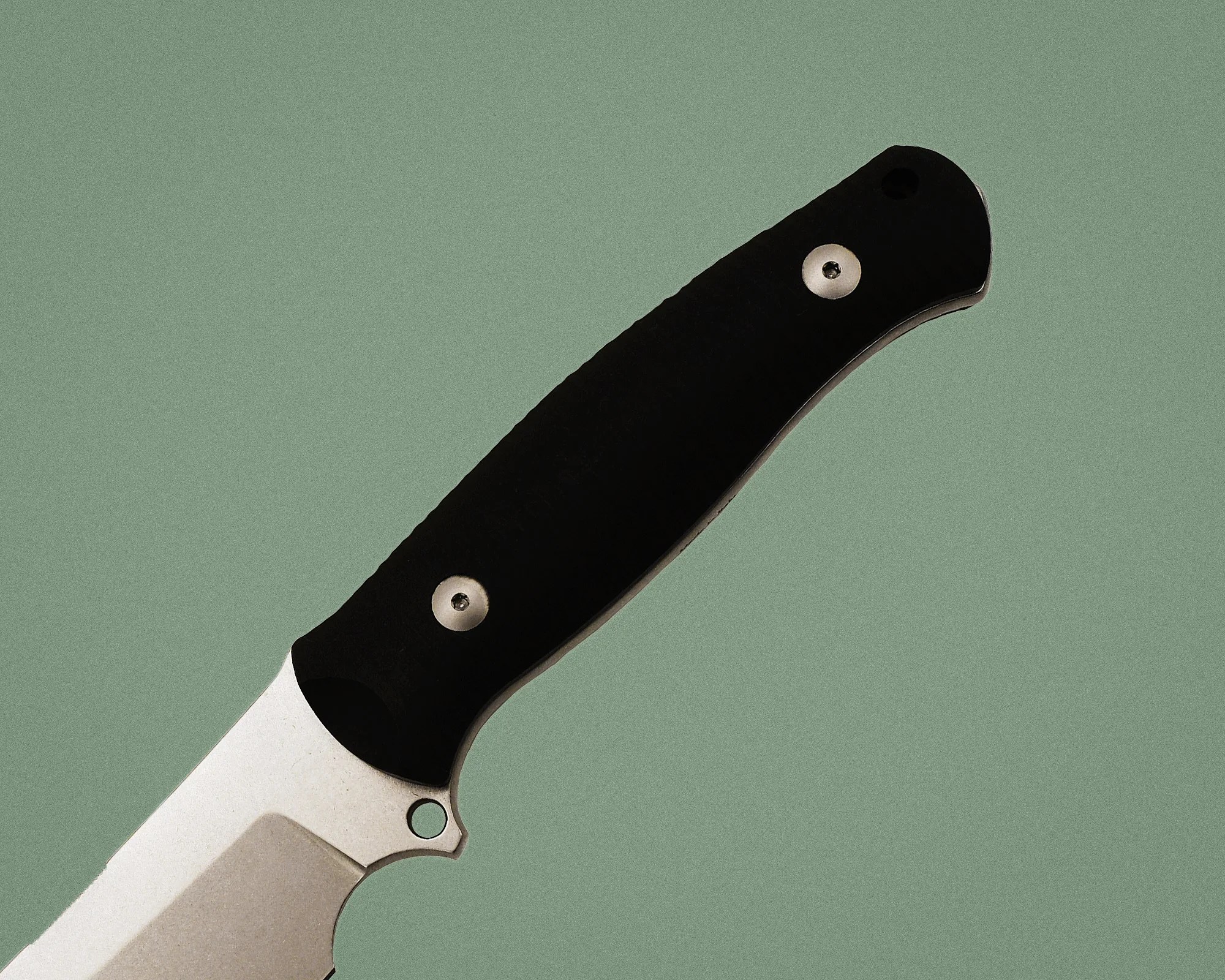 Knife with a black handle and silver blade on a green background.