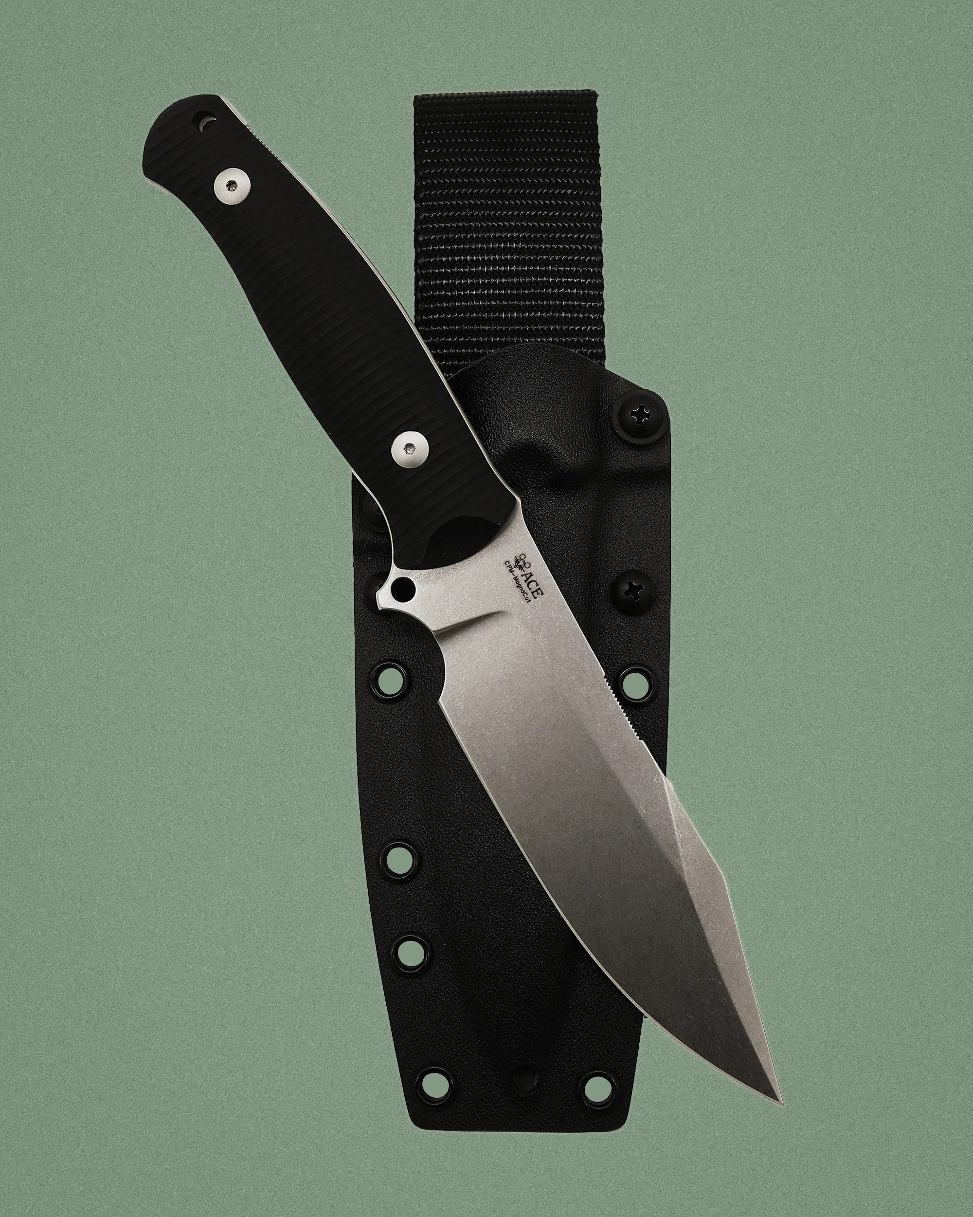 Fixed-blade knife with a stonewashed blade and black textured handle resting on a black sheath with a belt loop.