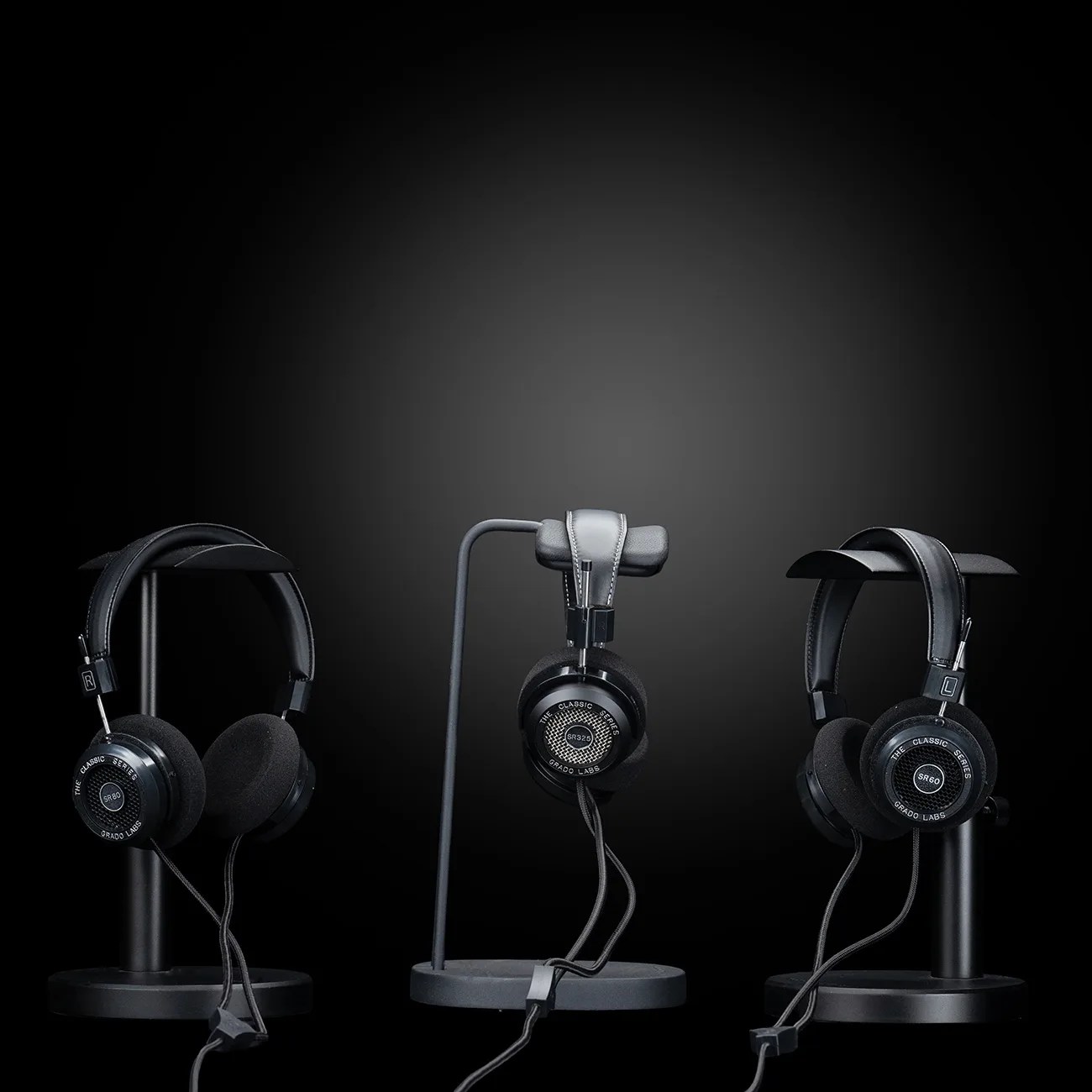 Three black Grado Labs headphones from The Classic Series (SR80, SR325, SR60) on black headphone stands against a dark gradient background.