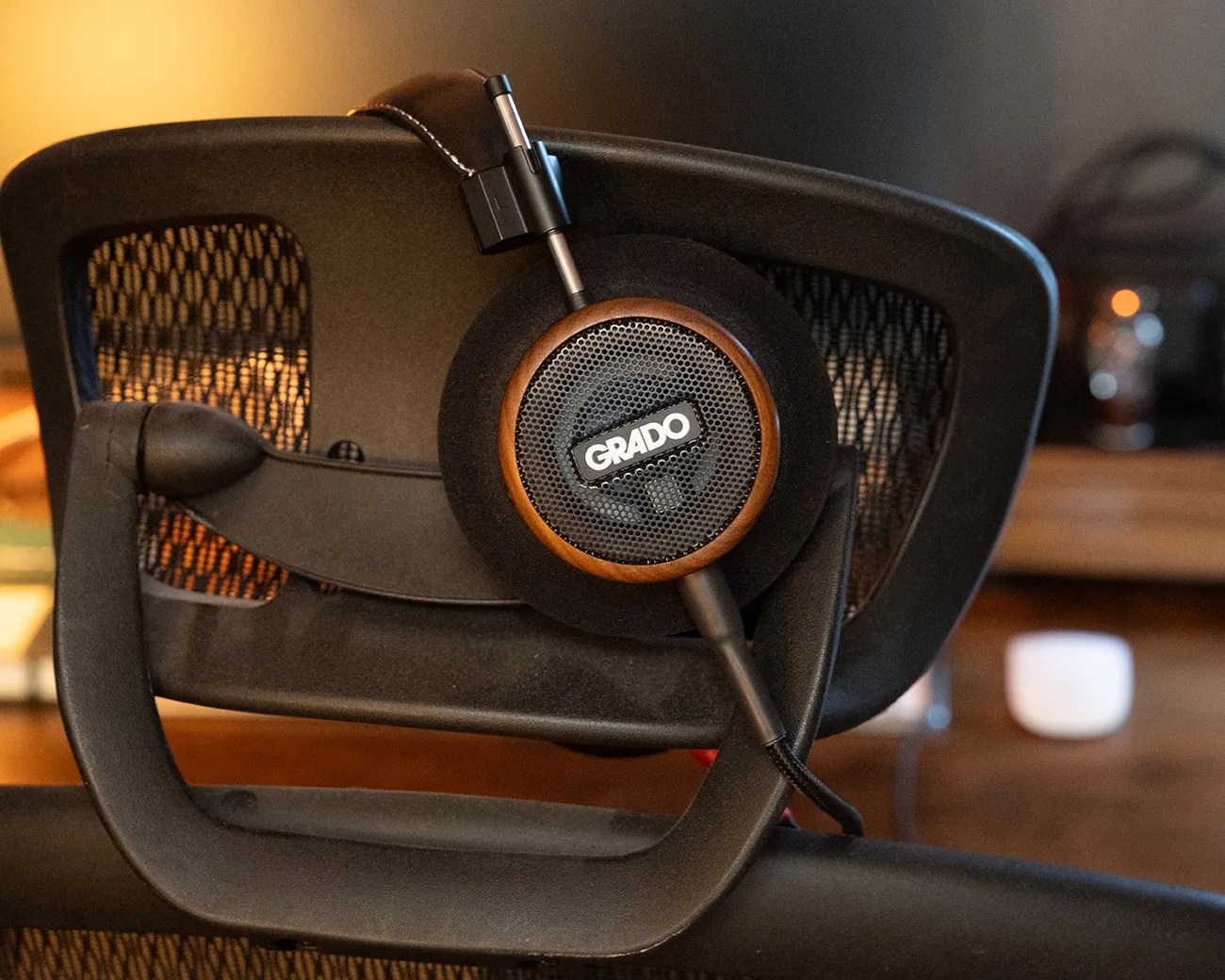 Grado headphones with wooden ear cups resting on a black mesh office chair.