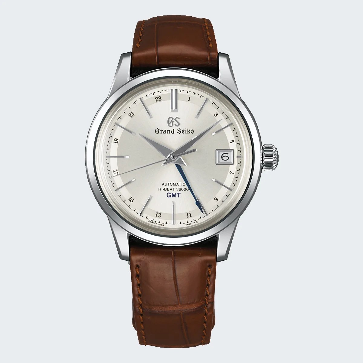 Silver Grand Seiko wristwatch with cream dial, blue GMT hand, date window, and brown leather strap.