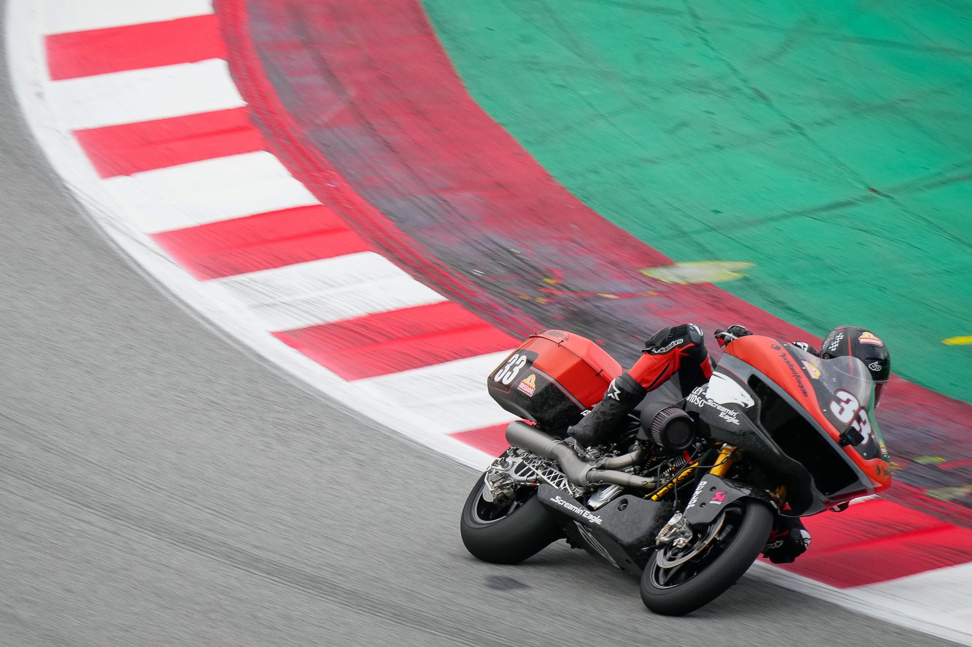 Racing motorcycle with number 33 leaning into a corner on a track with red and white curbs.