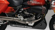 Close-up of a red Harley-Davidson motorcycle engine with black and silver exhaust pipes and "Screamin' Eagle" text on the lower fairing.