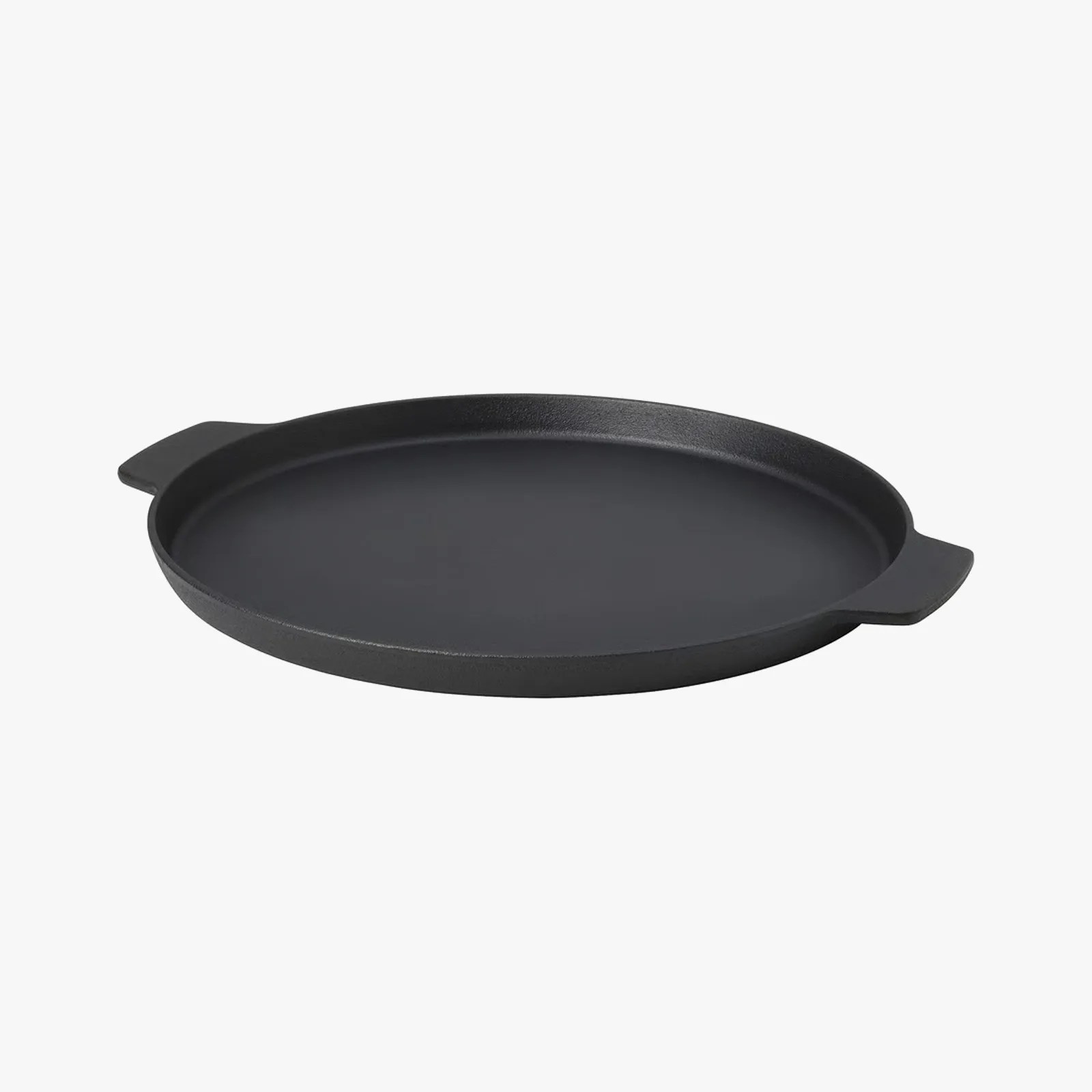 Round black cast iron griddle pan with two flat handles on a white background.