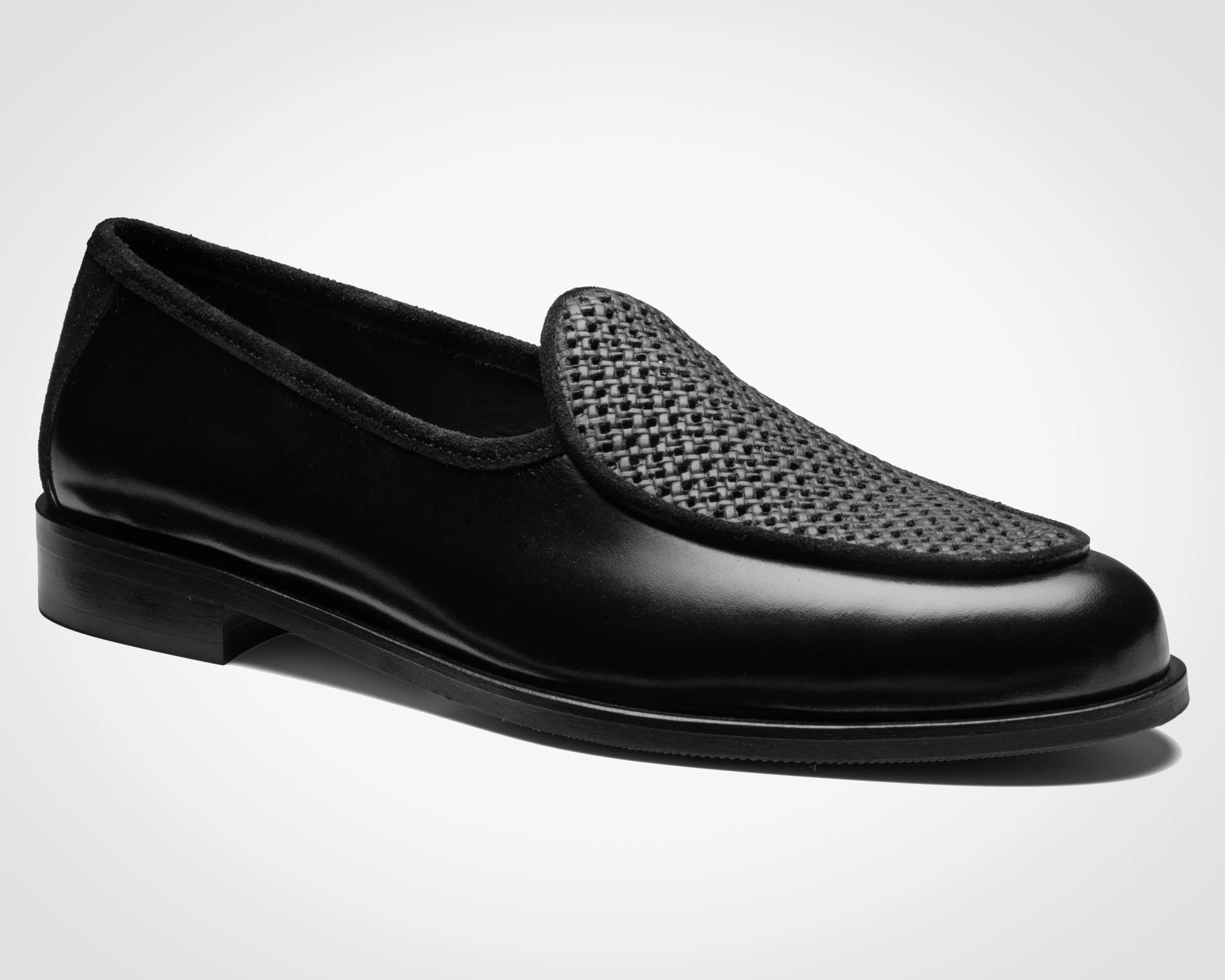 Black leather loafer with woven textured vamp and low heel on a white background.