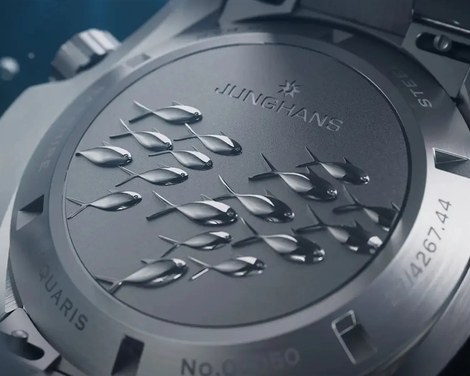 Close-up of a stainless steel Junghans watch back with embossed fish design and engraved text.