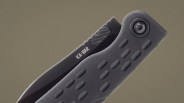 Black KA-BAR folding knife with textured grip handle and partially visible serrated blade.