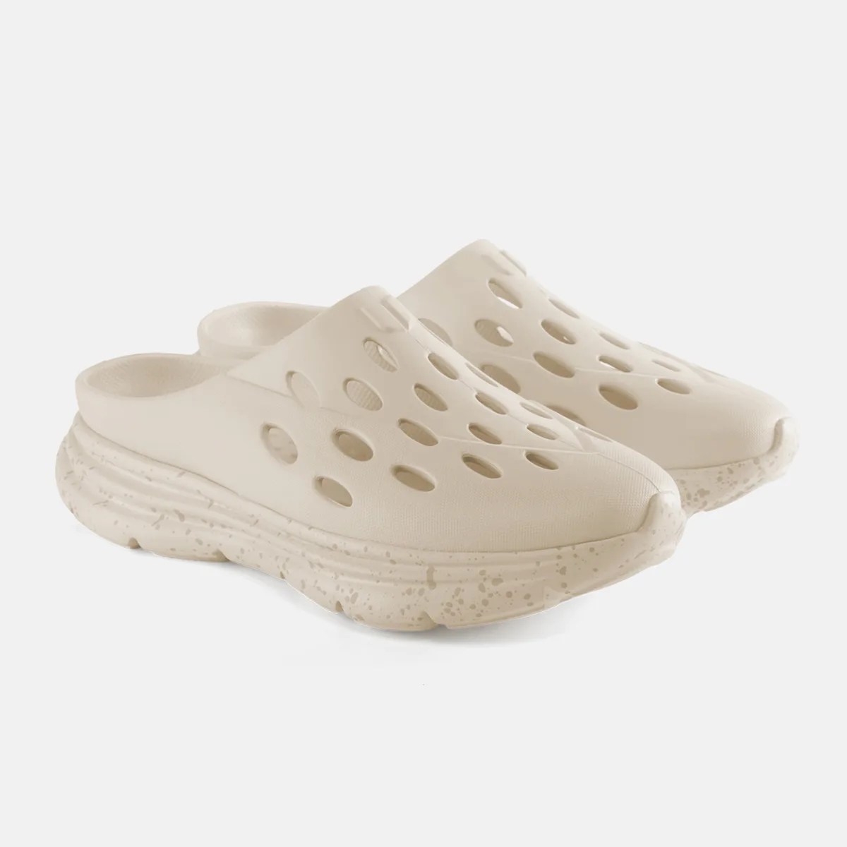 Pair of beige slip-on clogs with oval ventilation holes and speckled thick soles.