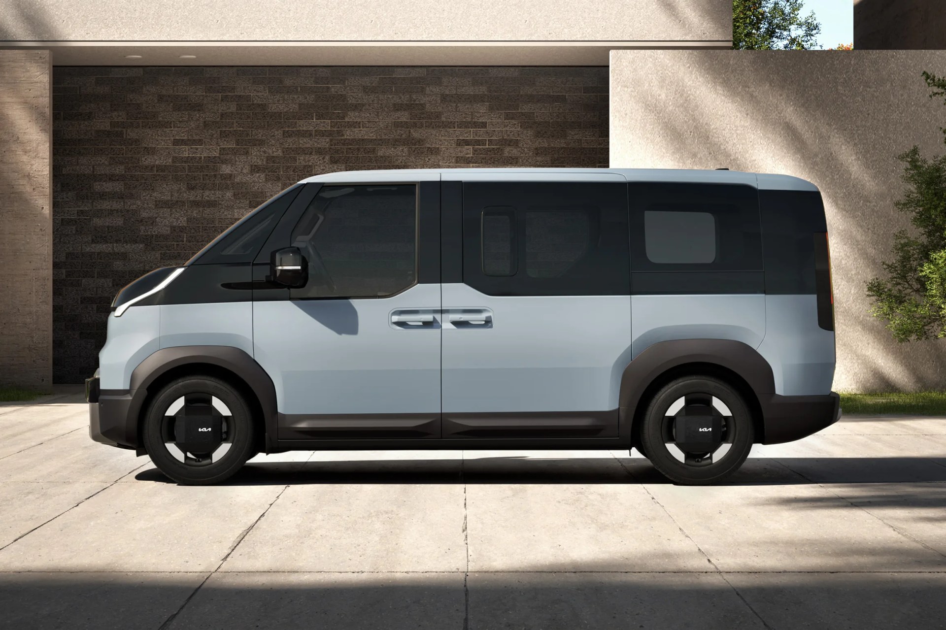 Light blue compact electric van with black tinted windows and black wheel covers parked on a concrete driveway.