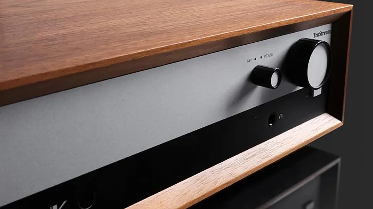 Close-up of a wooden-cased audio device with two black control knobs on a silver and black front panel.