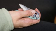 Hand holding a partially open Leatherman folding knife with a turquoise handle.