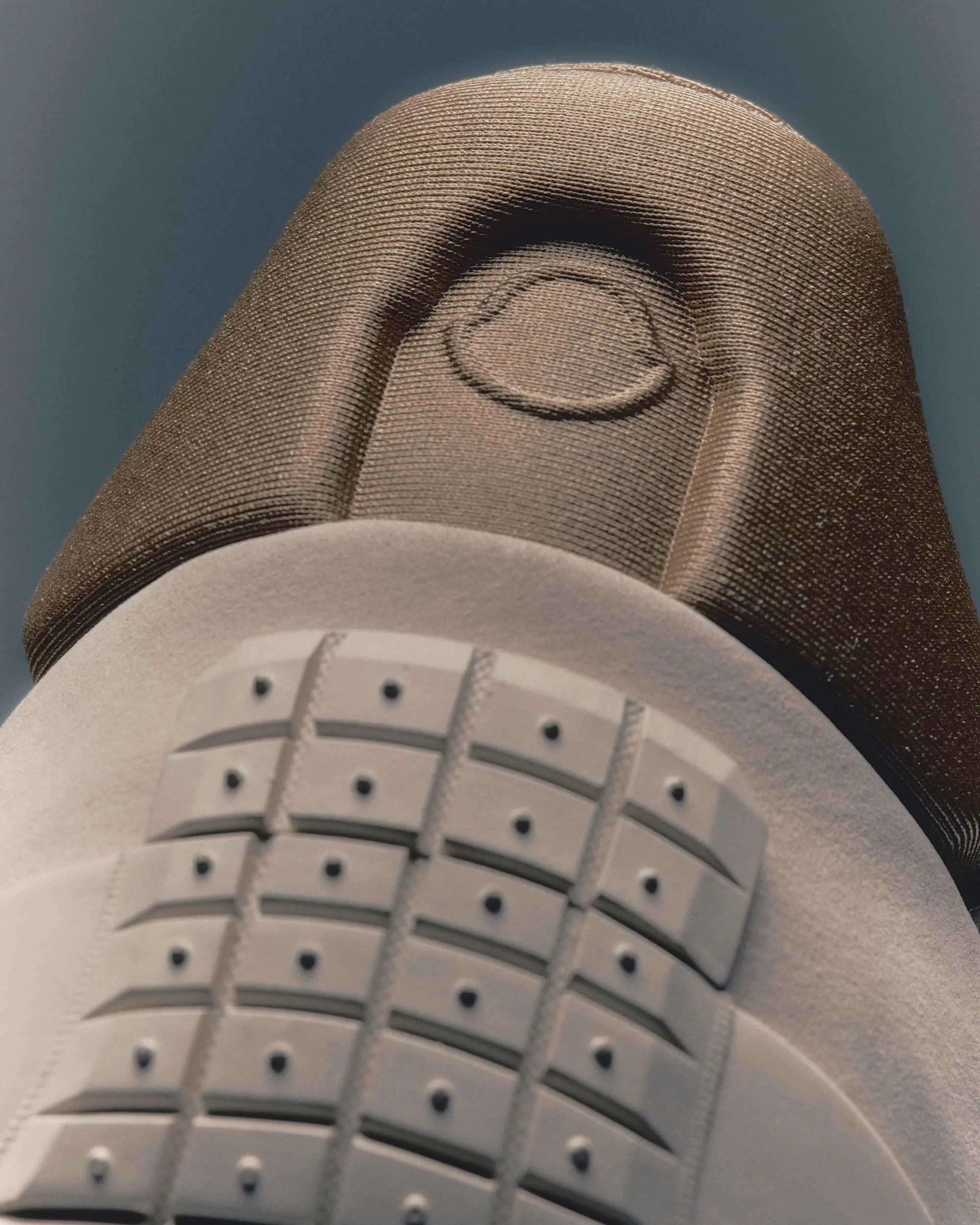 Close-up of a brown and white sneaker sole with a textured grip pattern and a circular logo on the brown fabric.
