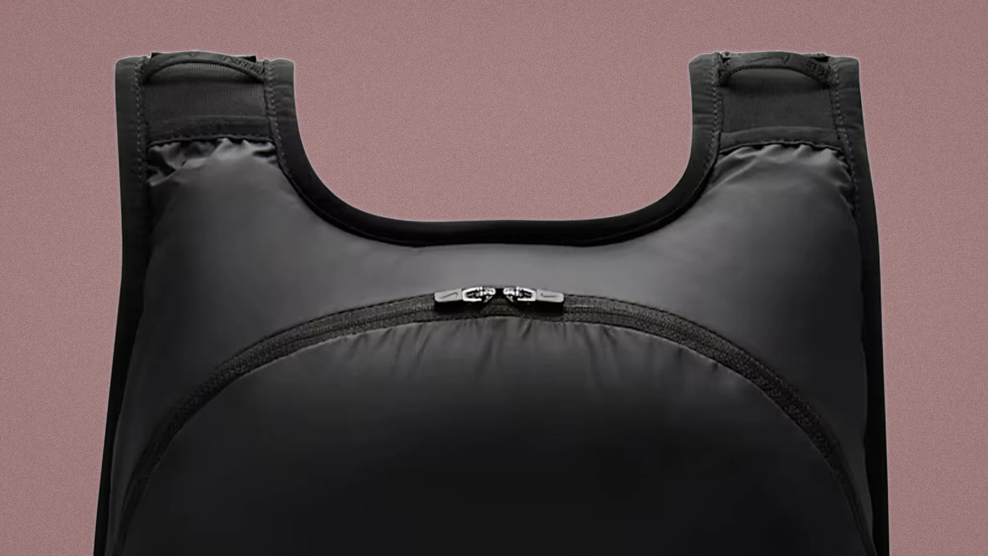 Black padded vest with a front zipper pocket and wide shoulder straps against a brown background.