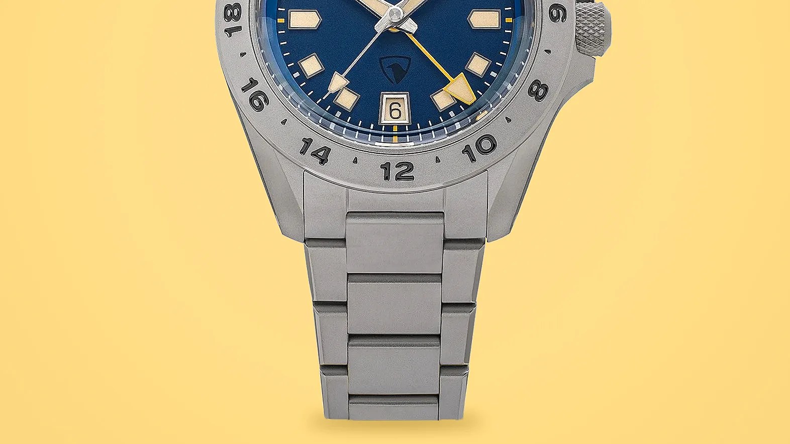 Close-up of a silver metal watch band and part of a blue watch face with a date window and yellow second hand.