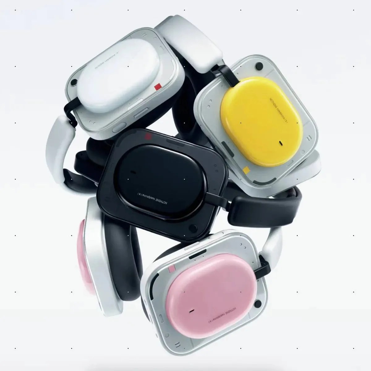 Four pairs of square-shaped headphones with rounded ear cups in white, yellow, black, and pink colors stacked together.