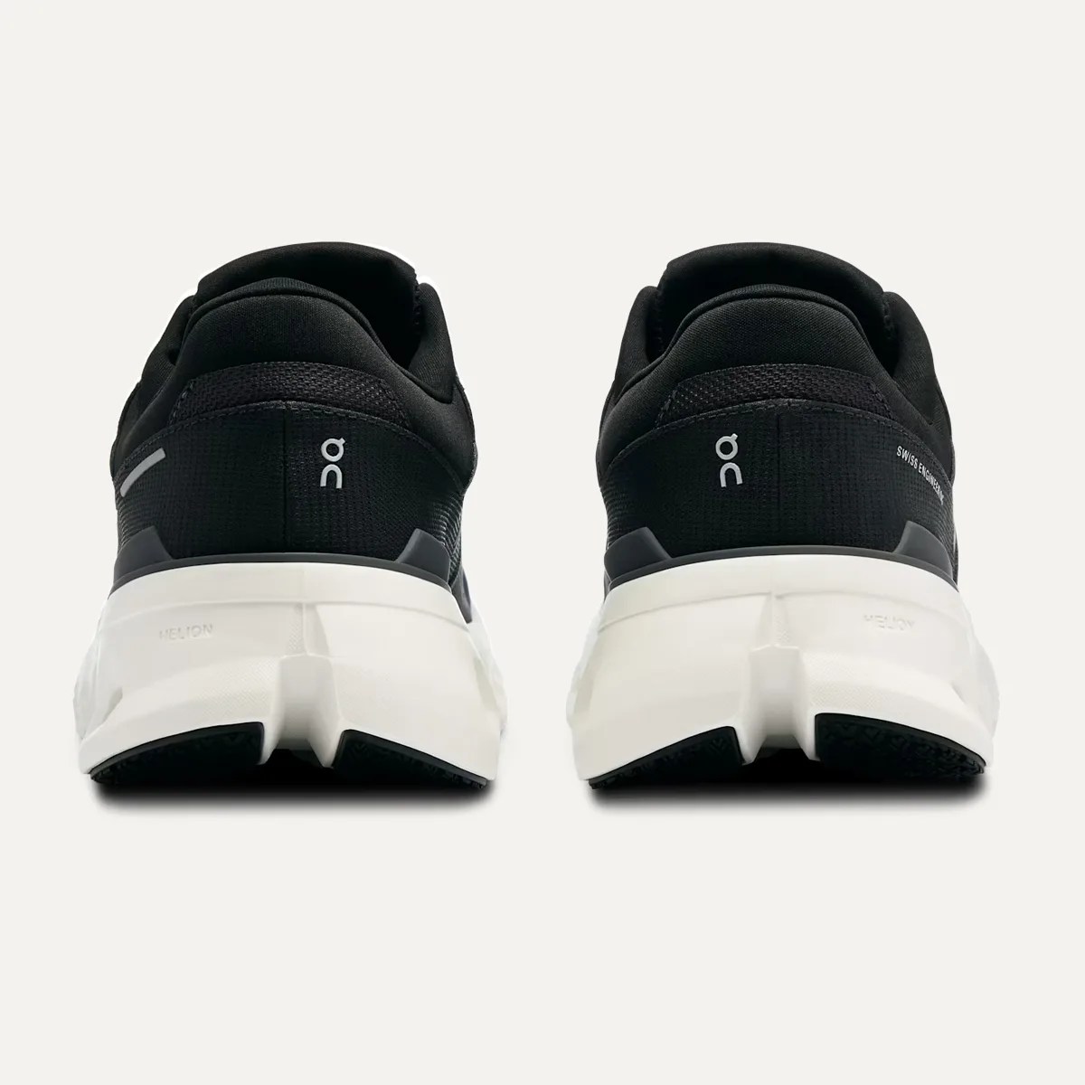 Pair of black and white On running shoes shown from the back with white midsoles and black outsoles.