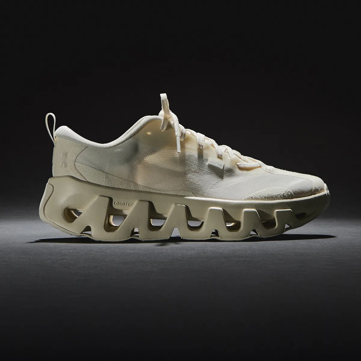 Beige athletic shoe with translucent upper and uniquely sculpted sole with cut-out sections.