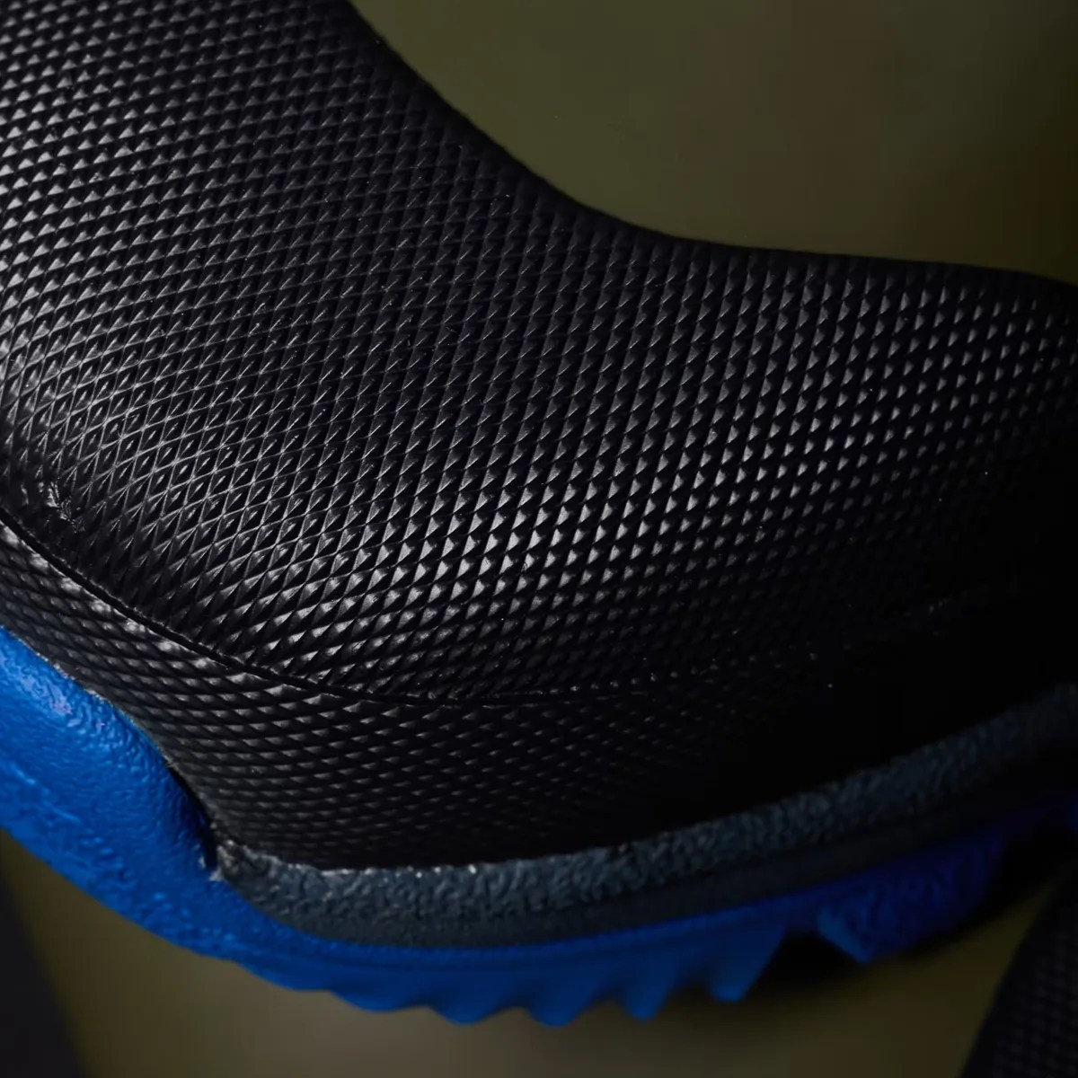 Close-up of a black textured shoe upper with a blue sole edge.