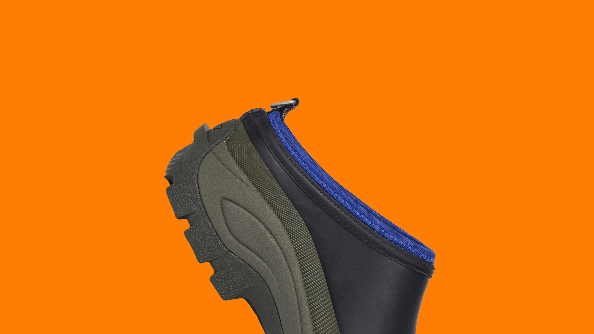 Black and olive green slip-on shoe with blue trim and rugged sole on an orange background.