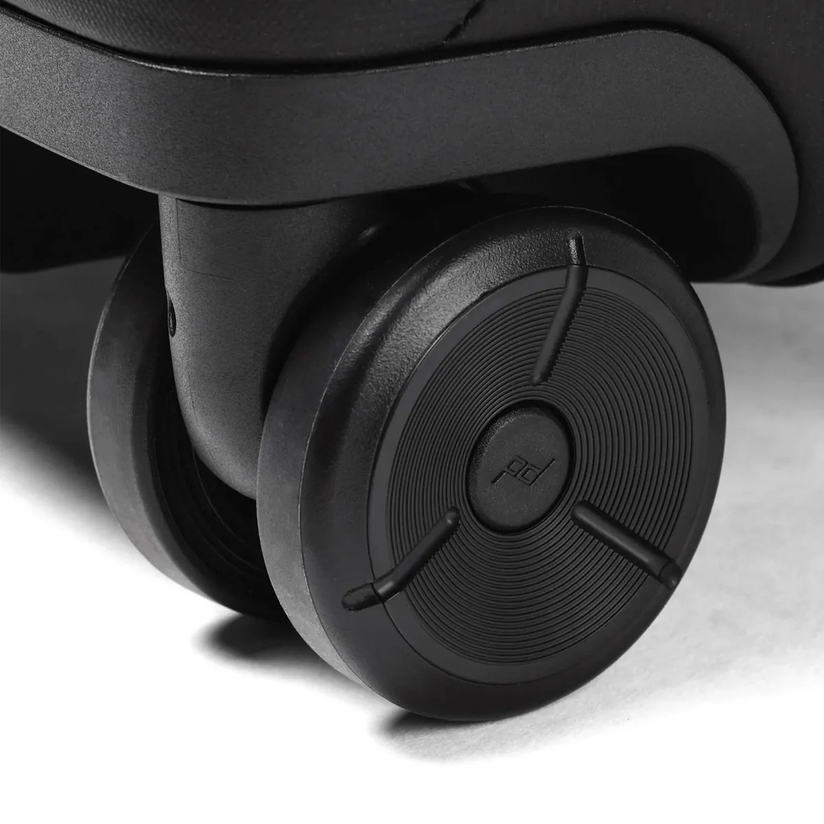 Close-up of a black dual spinner suitcase wheel with textured circular design and "pd" logo in the center.