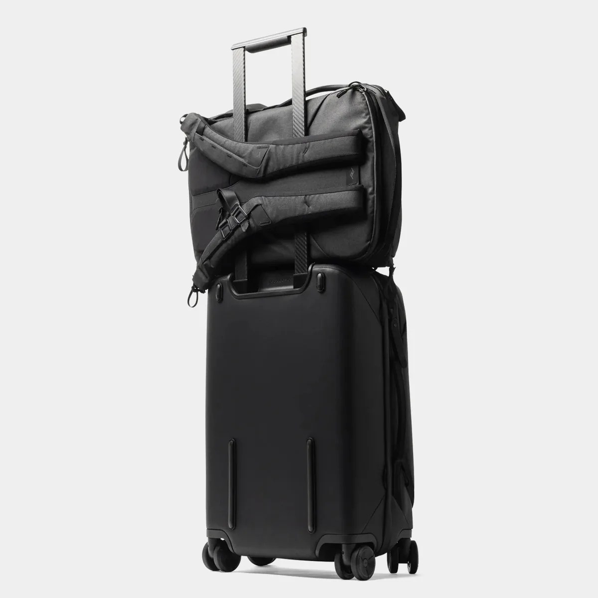 Black hard-shell rolling suitcase with a black backpack attached to the extended handle.