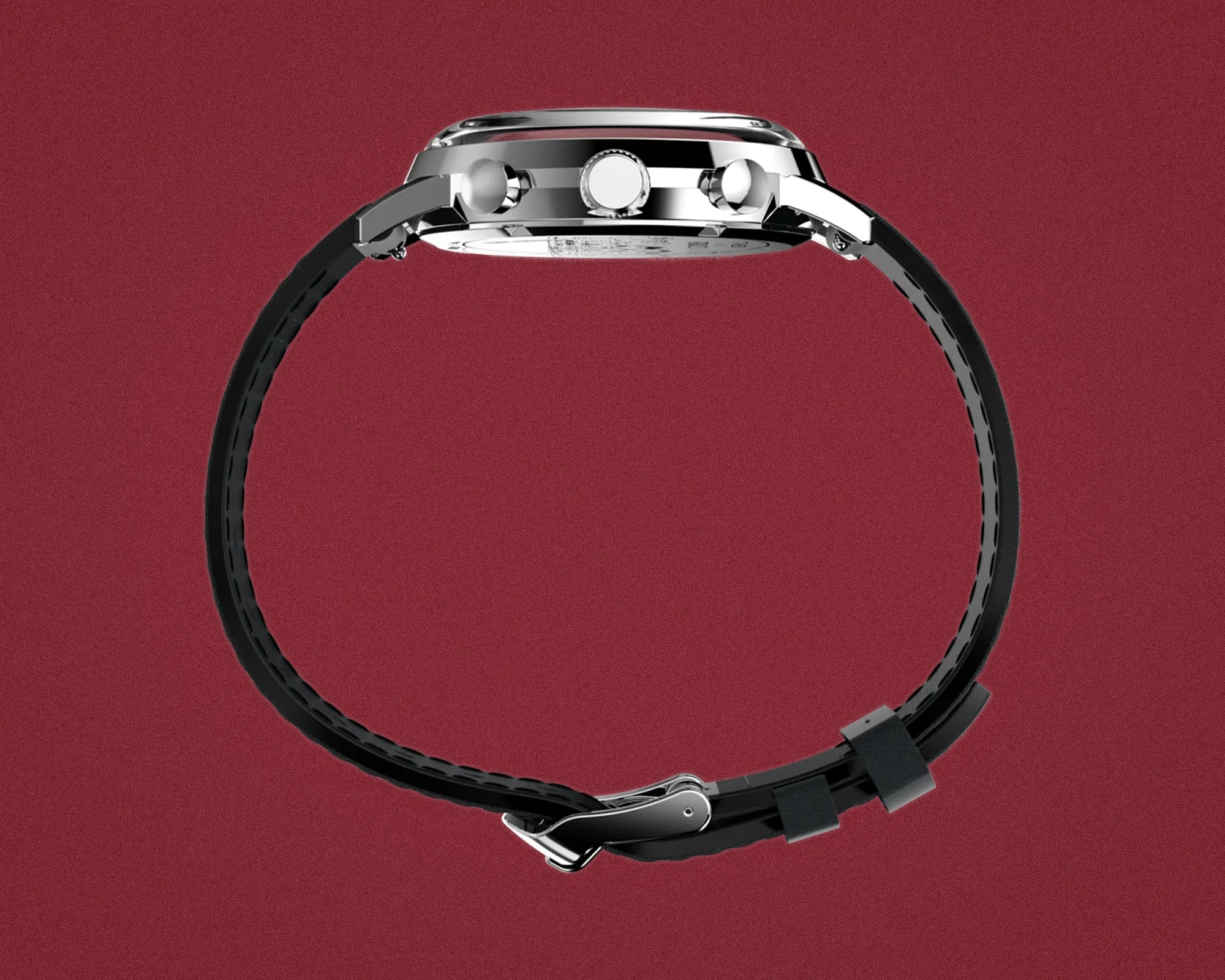 Side view of a silver chronograph watch with black leather strap and buckle on a red background.