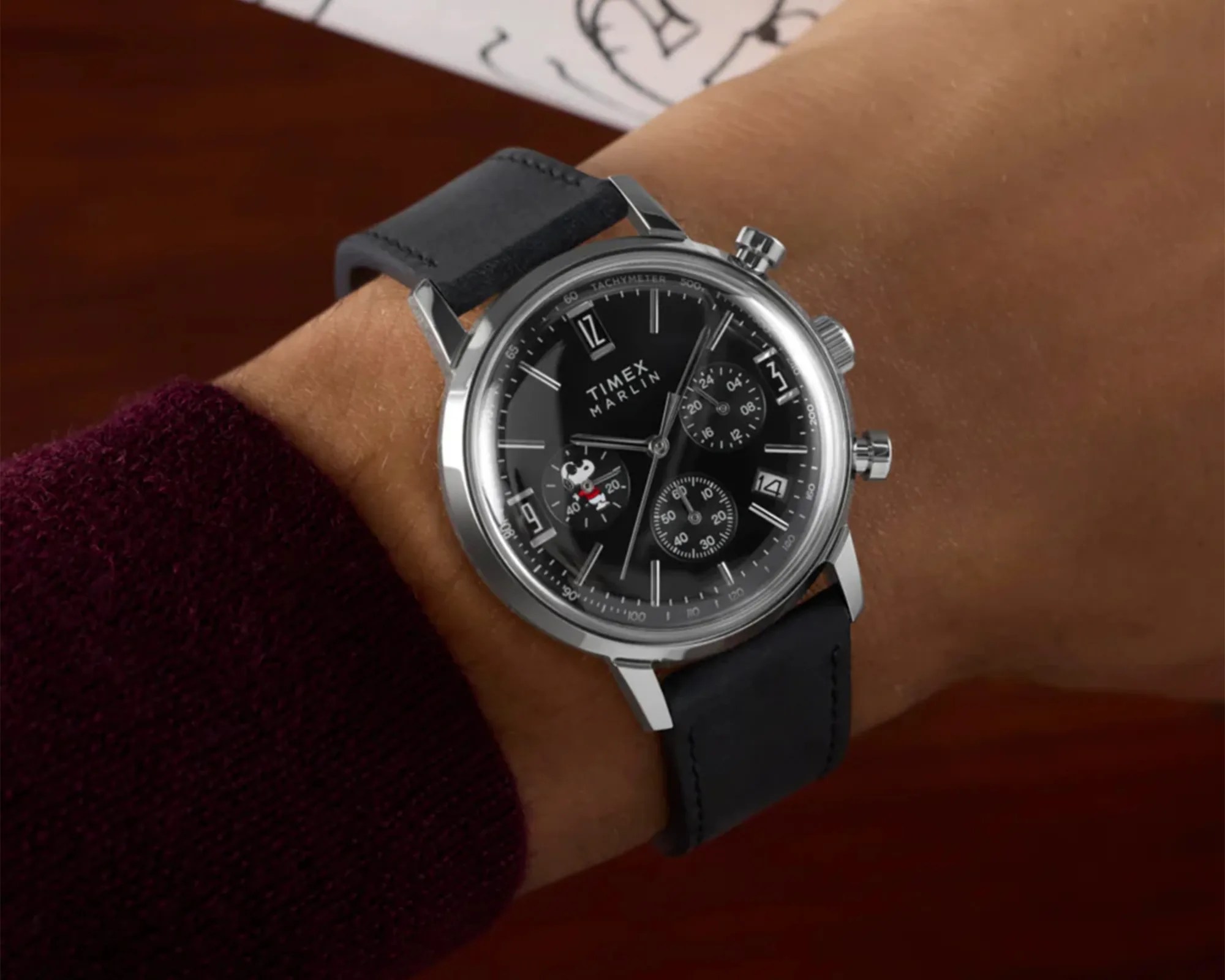 Timex Marlin wristwatch with black dial, silver case, black leather strap, and Snoopy character on subdial.