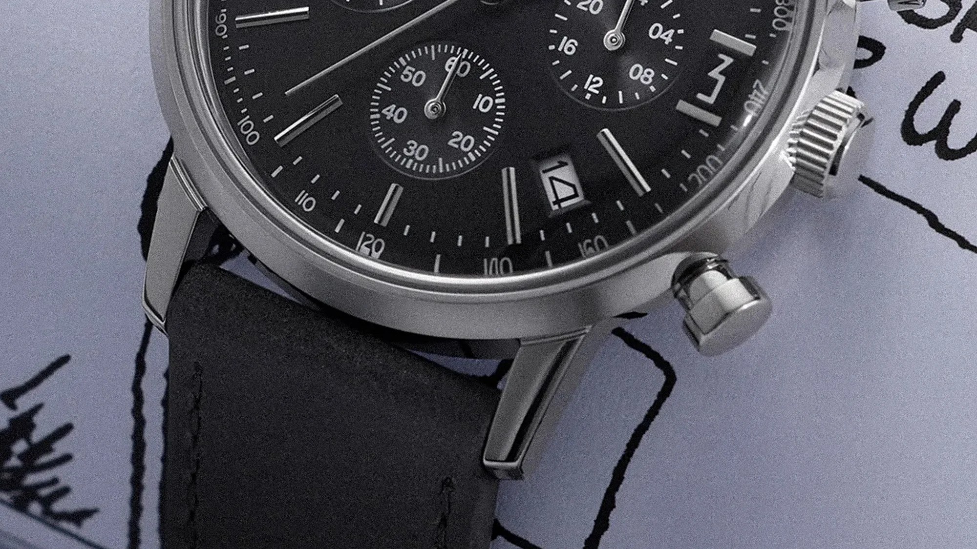 Close-up of a black chronograph watch face with silver markers, date window showing 14, and black leather strap.