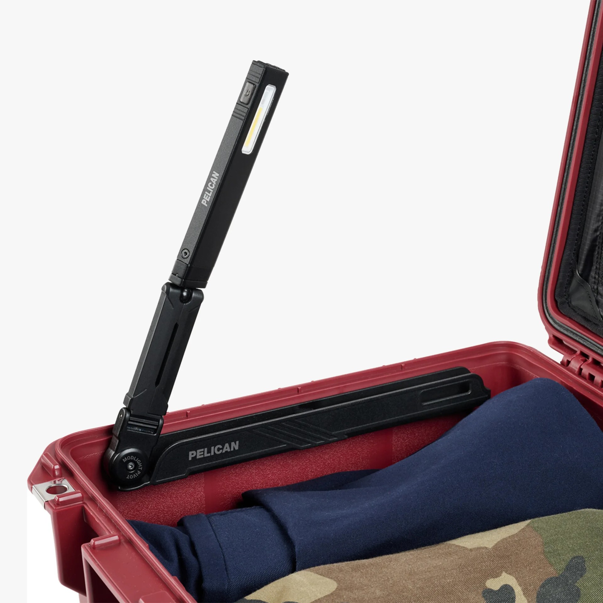 Black foldable Pelican LED light attached inside a red hard case with folded clothes.